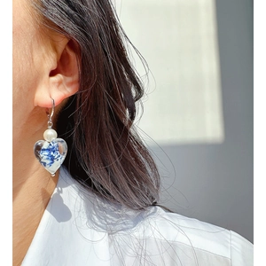 Elegant pearl and blue pattern glass heart earring set worn by a model for a vintage look