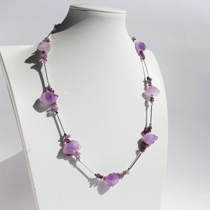 Necklace set featuring irregular purple raw ores and silver tubes on a display stand