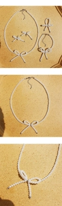 Detail of white pearl bow jewelry set including necklace, bracelet, ring and earrings