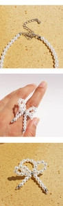 Detail of pearl necklace lobster clasp and bow ring made of cream pearls and silver metal