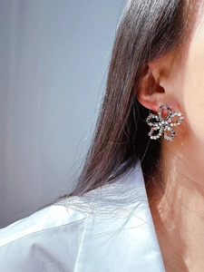 Close-up of silver hollow floral earrings made of tiny metallic discs on a model