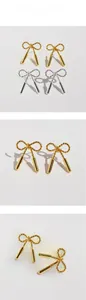 Detail view of twisted rope bow earrings with metallic cylinders in gold and silver
