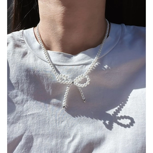 Elegant pearl bow necklace featuring small white beads and silver metal finish details