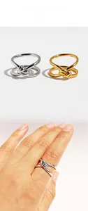 Detailed view of gold and silver double-layered knotted rings on hand and display