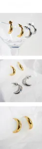 Close-up of chunky gold and silver crescent hoop earrings with a polished metal finish