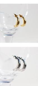 Polished C-shaped crescent earrings in gold and silver finish on glass edge detail