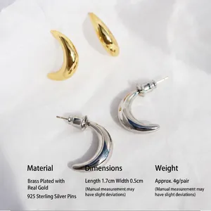 Polished gold and silver crescent C-shaped stud earrings on textured white paper