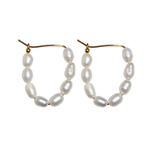 Boucles d'oreilles dorées en U faites main avec sept perles d'eau douce sur fond blanc