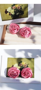 Dettaglio di orecchini a rosa in raso rosa fatti a mano con trama in seta su sfondo d'arte
