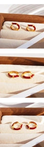 Macro view of gold hoop earrings with burgundy enamel and sparkling cubic zirconia stones