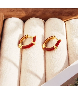 Detailed macro view of U-shaped burgundy enamel earrings with cubic zirconia on velvet box