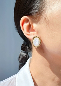 Gros plan de boucles d'oreilles ovales rétro avec fini irisé et bord doré torsadé sur l'oreille