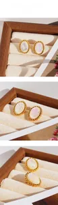 Détail des boucles d'oreilles ovales vintage avec pierre irisée et bordure torsadée dorée