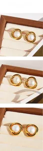 Detailed macro view of spiral gold metal studs featuring elegant white pearls on velvet