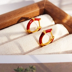 Luxury gold hoop earrings with red enamel and zircon on a white velvet jewelry box