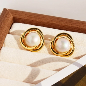 Elegant gold layered ring earrings with central pearl on a premium jewelry tray