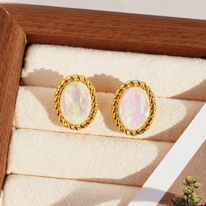 Boucles d'oreilles ovales irisées avec cadre doré torsadé sur un plateau à bijoux