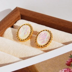 Boucles d'oreilles ovales dorées vintage avec centre irisé sur présentoir beige