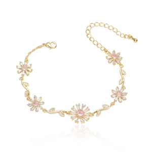 Elegant gold flower bracelet with pink gemstones and white crystals on reflective white surface