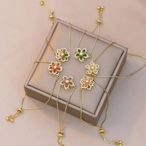 Adjustable gold bracelets with spinning zircon flower charms in six vibrant colors