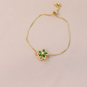Macro view of gold adjustable bracelet with green gemstone flower and box chain