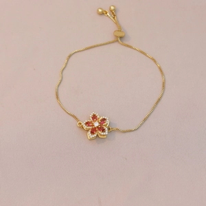 Detail of adjustable gold flower bracelet with red crystals and pull-string slider clasp