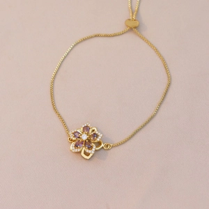 Detail of adjustable gold box chain with purple zircon flower and heart slider clasp