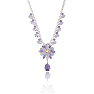 Collier floral élégant avec pierres violettes et jaunes sur surface réfléchissante