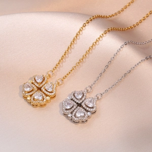 Gros plan du collier trèfle magnétique avec zircons sur fond de satin couleur champagne