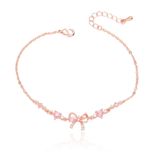 Détail macro du bracelet en or rose avec nœud en zircon rose et cristaux en forme de cœur