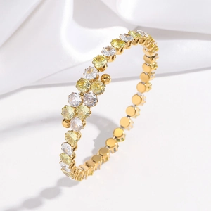 Détail d'un bracelet jonc doré poli orné de pierres de zircone blanches et jaunes éclatantes