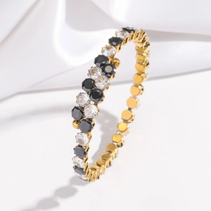 Détail d'un bracelet doré orné de zircons noirs et transparents alternés en gros plan