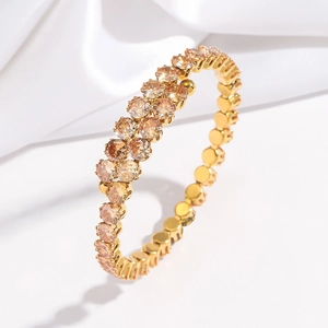 Détail d'un bracelet ouvert doré orné de rangées de zircons de couleur champagne