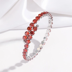 Vue détaillée d'un bracelet ouvert serti de pierres précieuses rouges sur métal argenté
