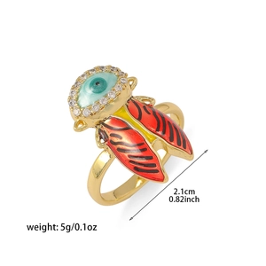 Detailed view of evil eye insect ring with orange enamel wings and white zircon halo