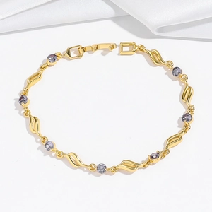 Dettaglio del bracciale dorato con maglie ondulate traforate e pietre di zircone viola