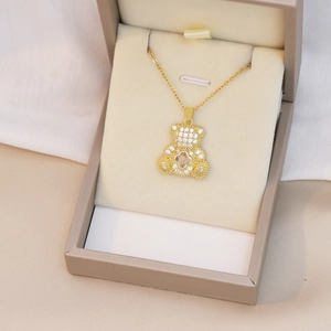 Gros plan détaillé du pendentif ours doré avec pavé de cristaux et fleur rose au centre