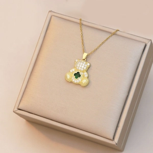 Détail macro d'un pendentif ours doré avec trèfle vert et pavé de zircons blancs