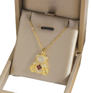 Pendentif ours doré avec zircons blancs et trèfle rouge dans un écrin à bijoux chic