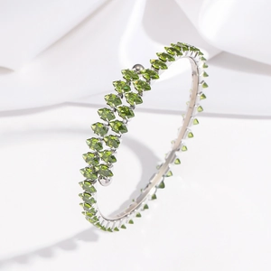Détail d'un bracelet ouvert serti de cristaux marquise vert olive sur fond de soie