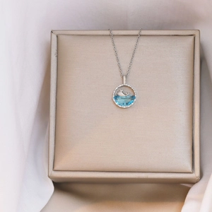 Elegant silver dolphin necklace with blue gemstone pendant on a jewelry gift box