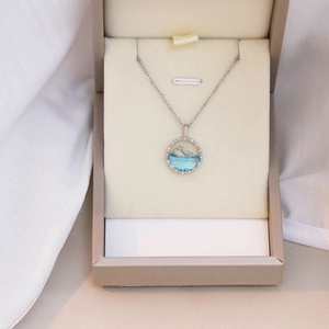 Detailed view of a silver whale pendant with ocean blue resin inside a jewelry box