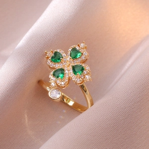 Close-up of golden clover open ring with emerald heart-shaped zircons and white crystals