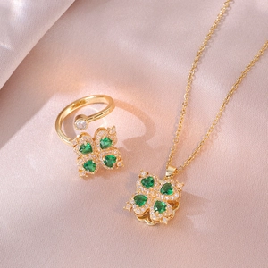 Golden clover jewelry set with green heart-shaped stones on champagne silk fabric