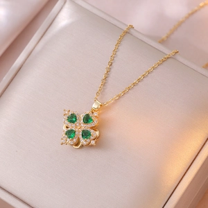 Detailed close-up of golden clover necklace with green zircon heart stones and fine O-chain