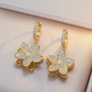 Orecchini a fiore dorati con zirconi e perle su un elegante sfondo in seta champagne