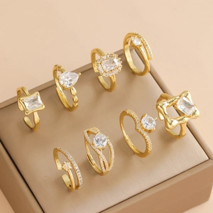 Lot de 8 bagues dorées avec zircons blancs présentées sur un écrin en cuir