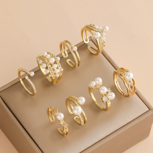 Lot de huit bagues dorées réglables avec perles et pierres en oxyde de zirconium brillants