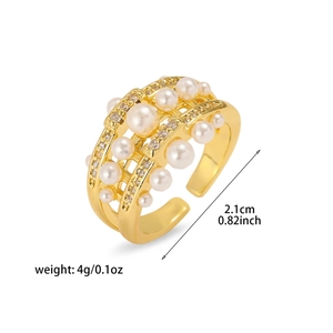 Détail d'une bague multicouche plaquée or ornée de perles blanches et zircons brillants