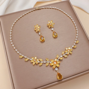 Elegant gold-tone flower jewelry set with yellow zircon pendants on champagne tray